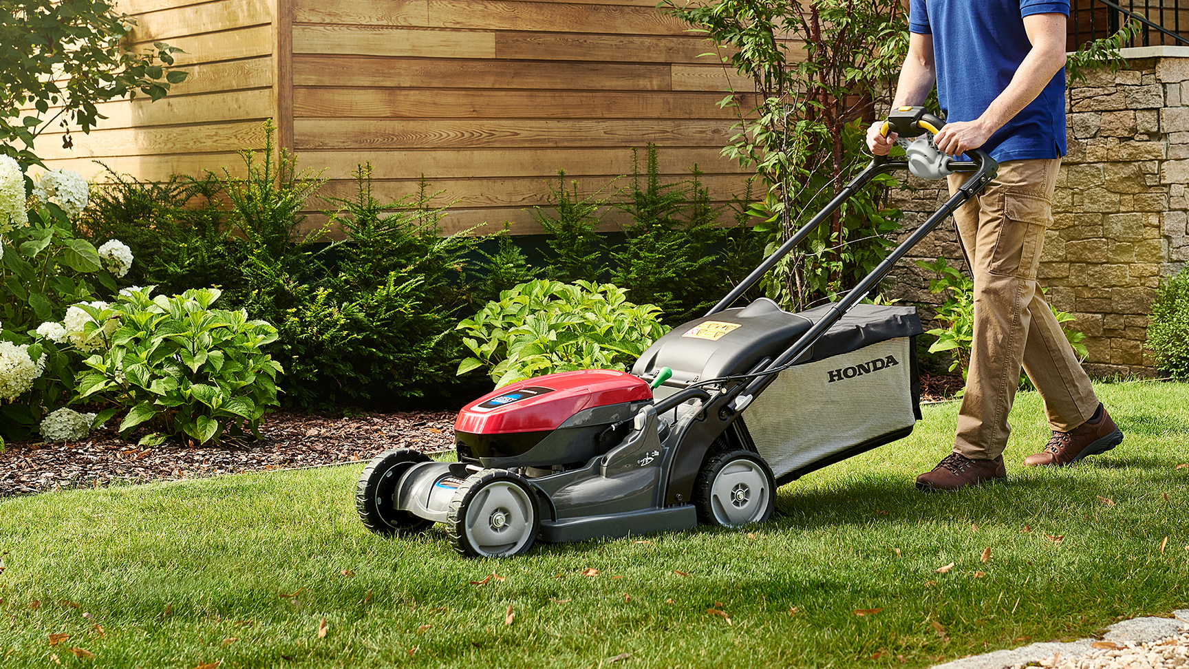 Uomo che spinge HRX a batteria in giardino.